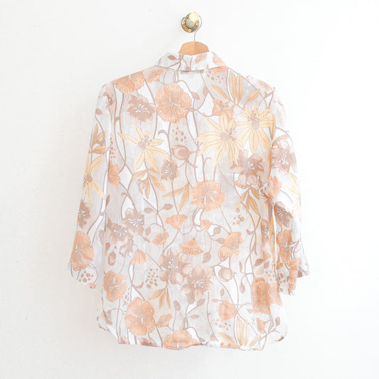 the back of a white vintage modissimo see-through vintage blouse with beige and orange flowers which is made in france
