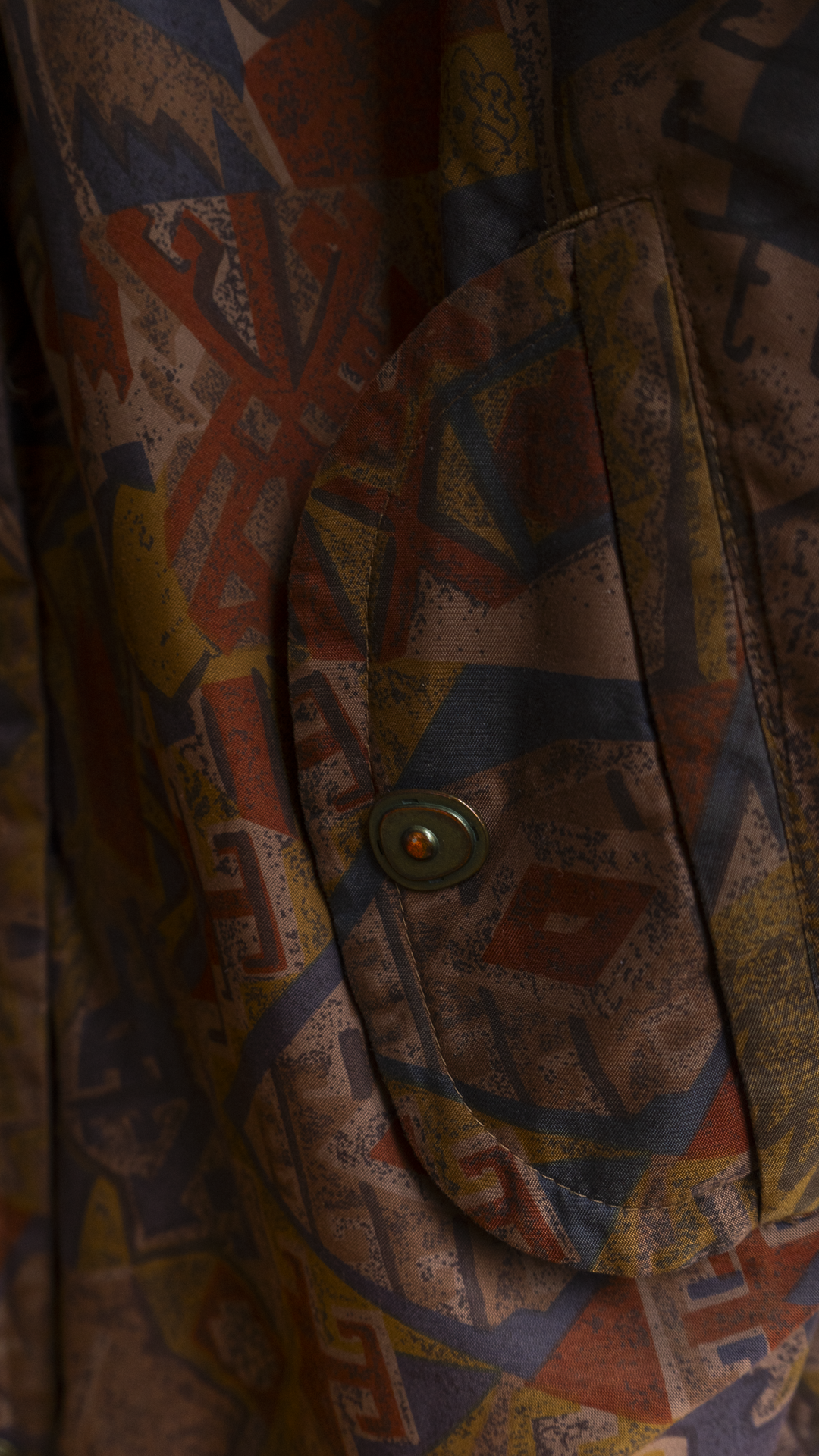 detail of pocket of an eighties patterned brown coat with a metal button Fresh Vintage