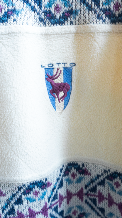 Close-up of a cream-colored 80s Lotto Sport Italia fleece indie sweater featuring an embroidered LOTTO shield logo in white and blue with a purple deer on it. 