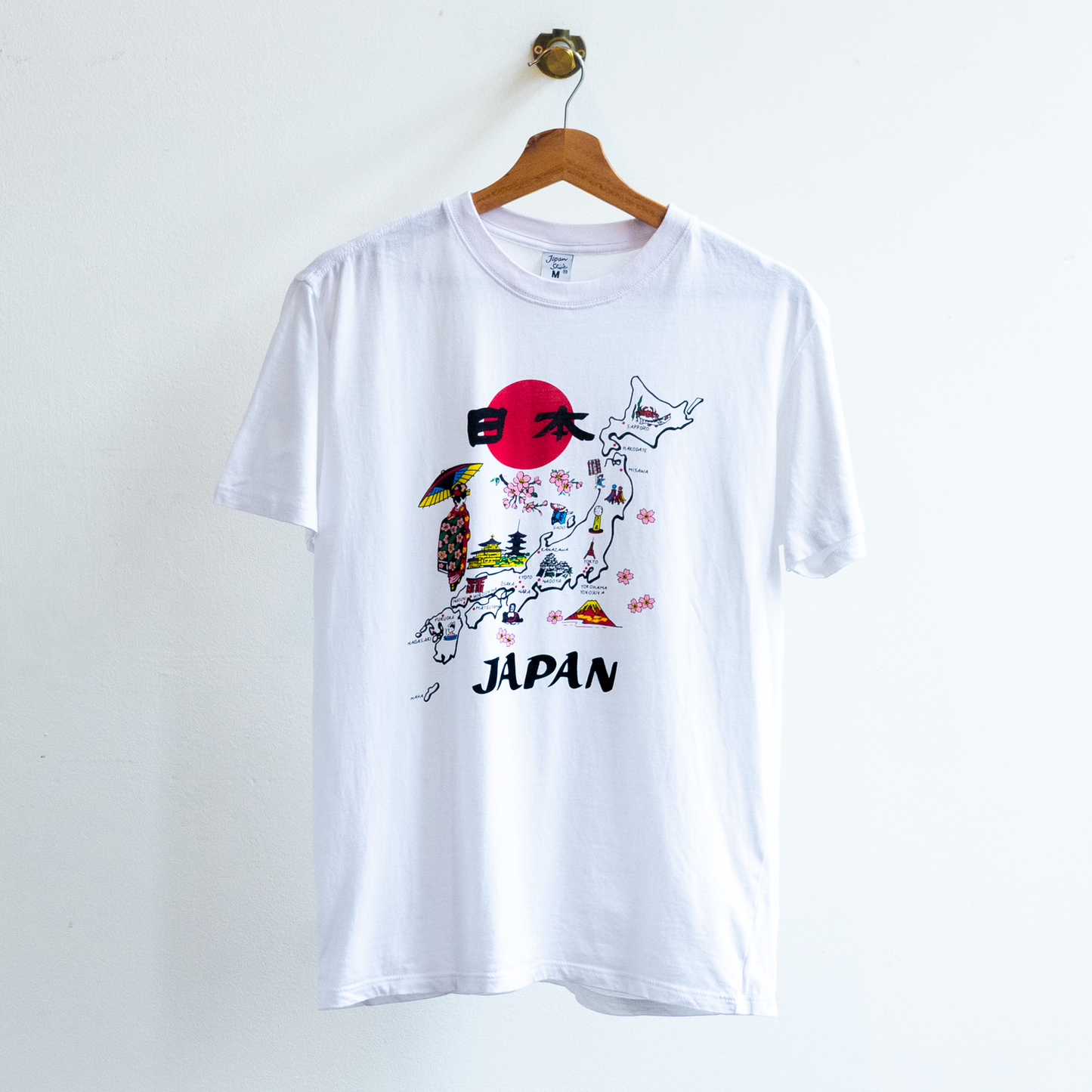 White secondhand t-shirt featuring a graphic print of the map of Japan with a red sun, cherry blossoms, and the word 'JAPAN' printed below.