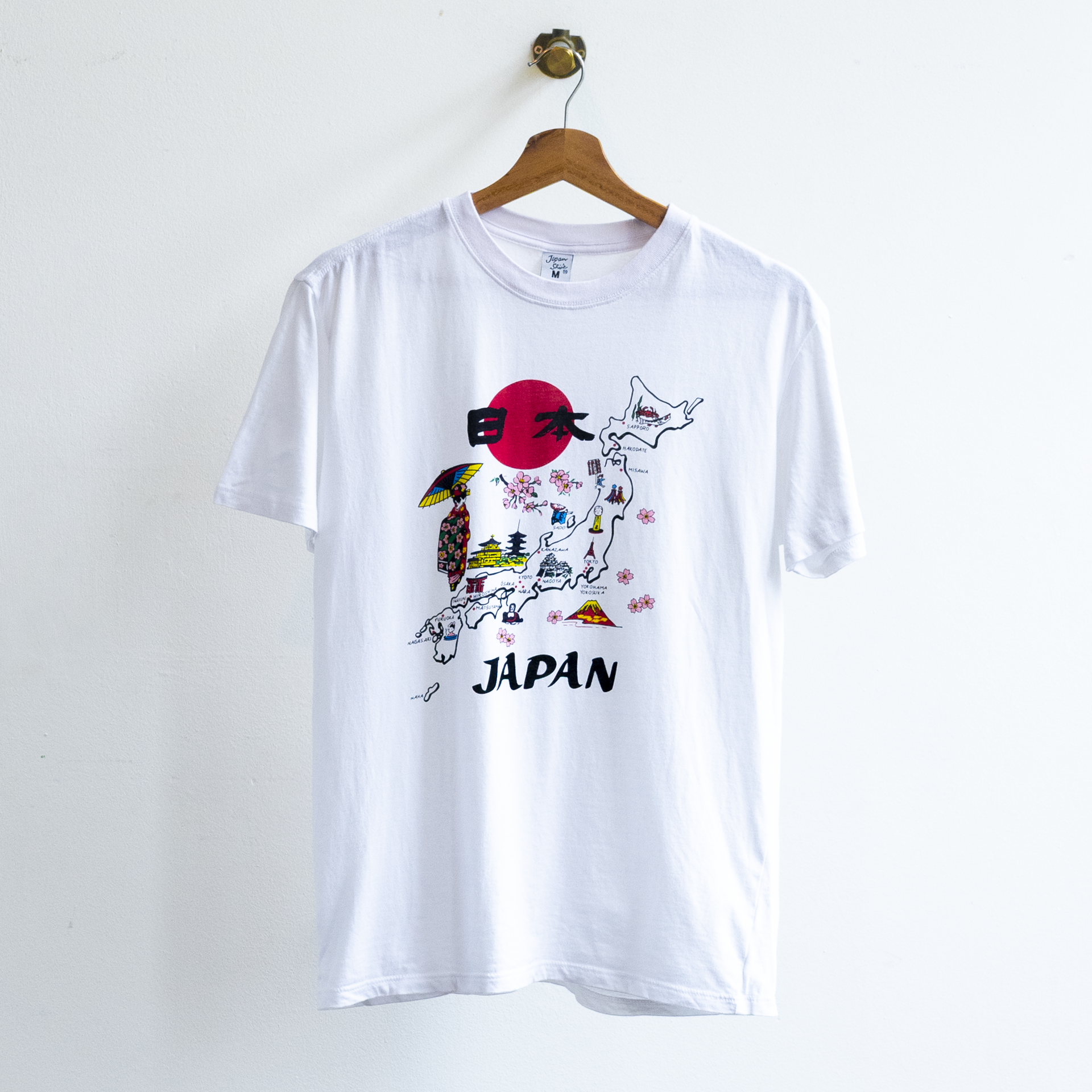 White secondhand t-shirt featuring a graphic print of the map of Japan with a red sun, cherry blossoms, and the word 'JAPAN' printed below.