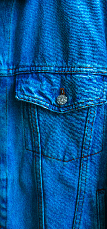 Close-up of a secondhand light blue denim jacket with a button