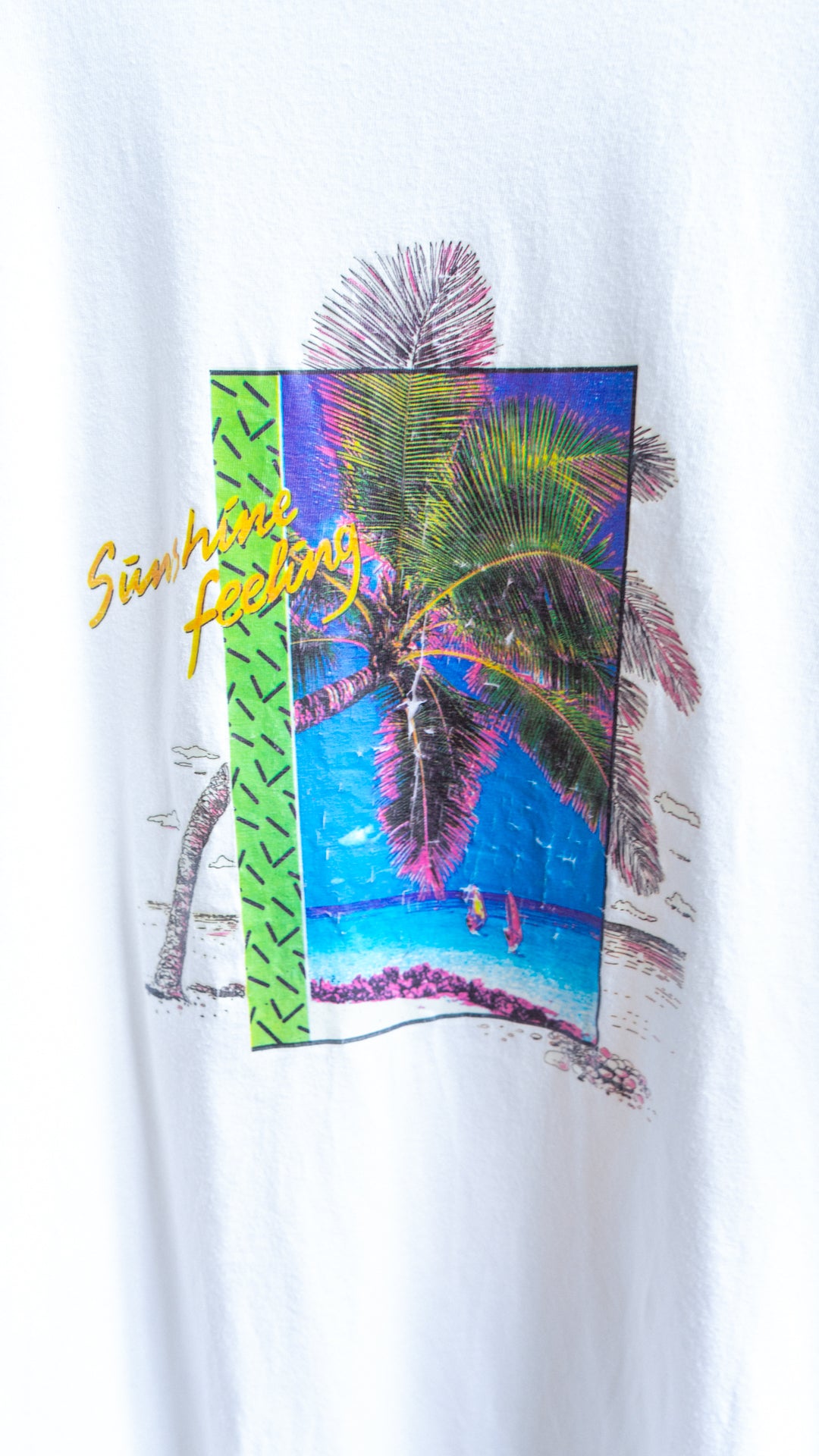 Grafische print met palmboom een zicht op de oceaan en tekst sunshine feeling in het geel op een witte vintage t-shirt
