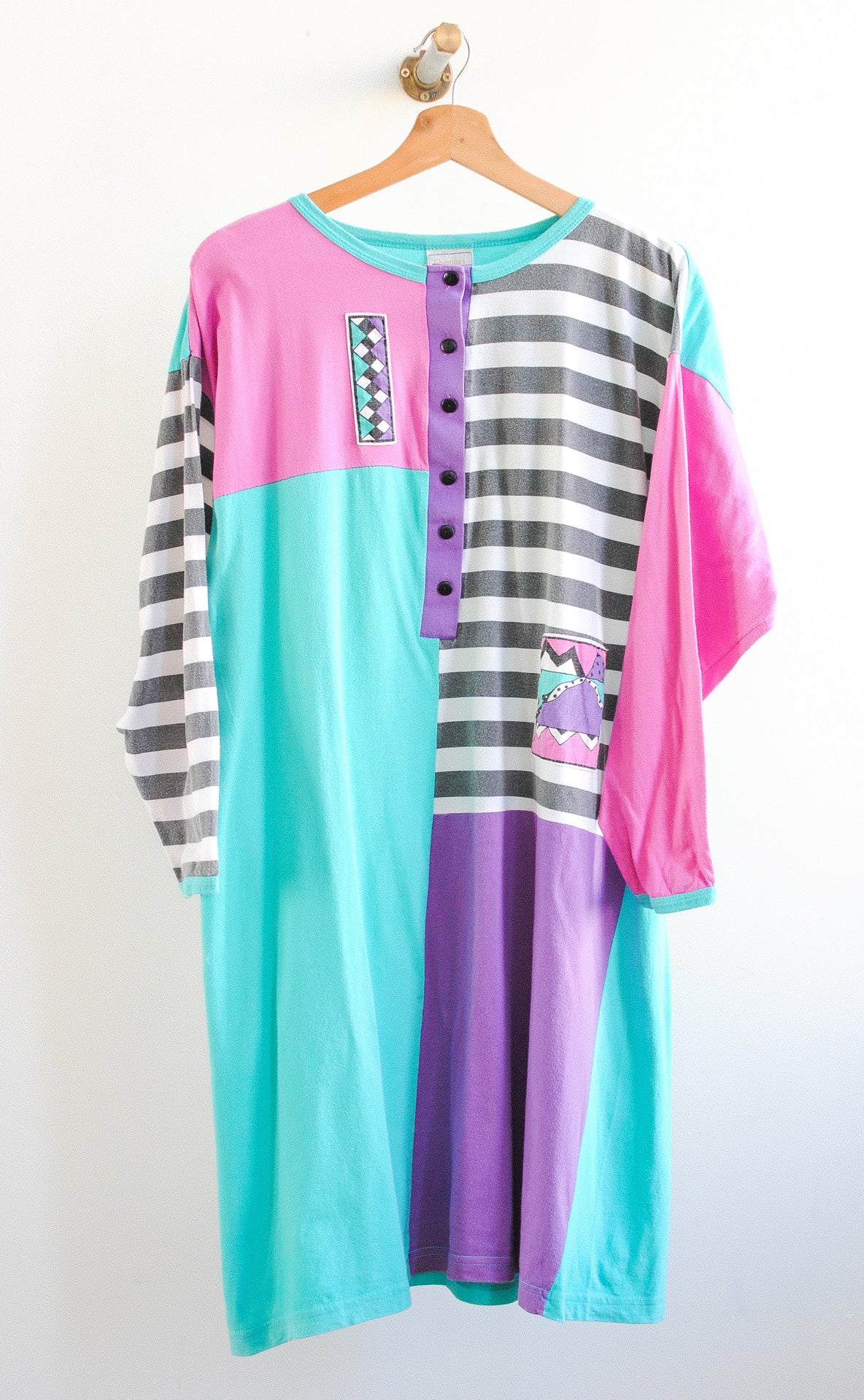 Colorful long vintage tshirt in blue pink purple black and white with buttons and stripes on a hanger 