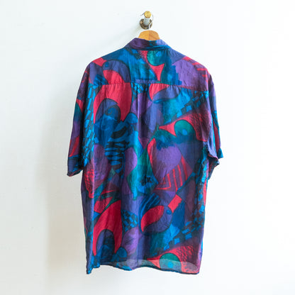 back of a colorful patterned abstract vintage shirt in dark blue purple green red in a soft fabric on a hanger