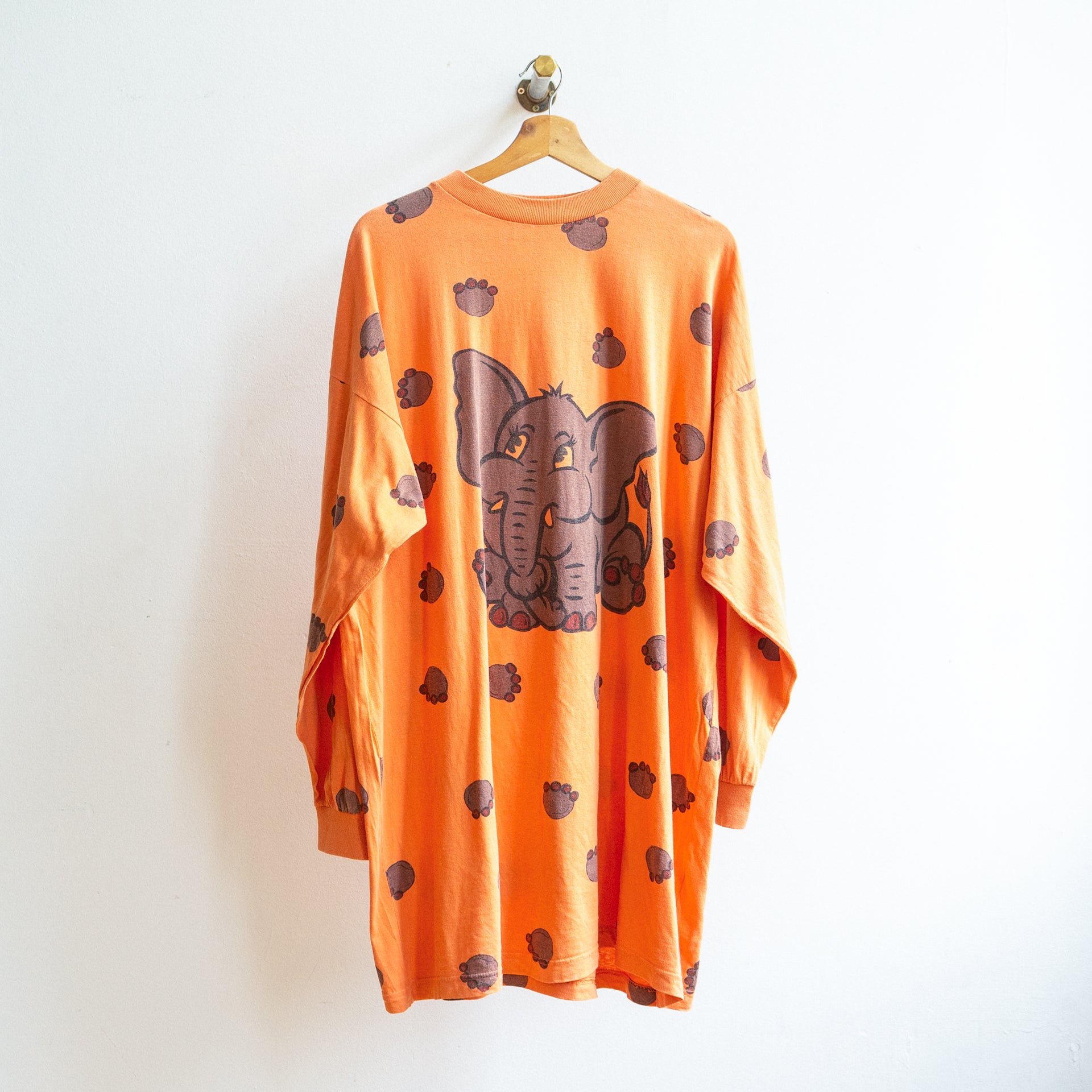 Oranje vintage oversized japon met lange mouwen en een afbeelding van een olifant en olifantenpootjes rondom aan een kapstok
