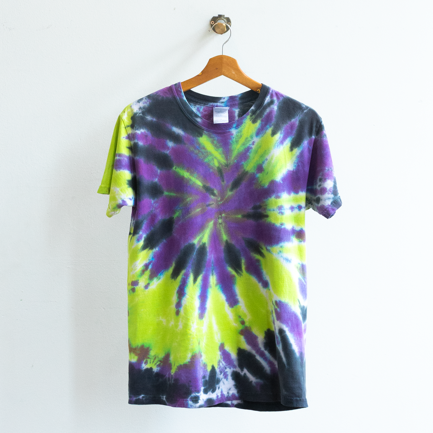 A short-sleeve vintage grunge tie-dye t-shirt with a spiral pattern in purple, lime green, and black
