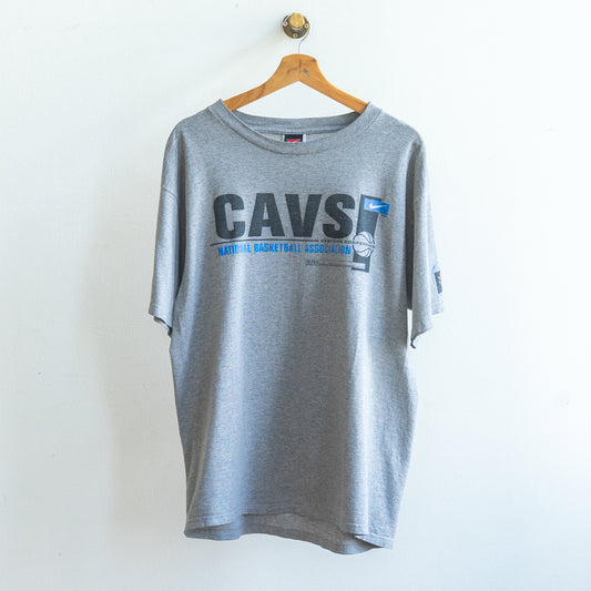 grijze vintage Nike basketbal t-shirt met hoofdletters CAVS in het zwart rechts een kleiner wit nike logo op blauwe achtergrond en blauwe letters national basketball association en een afbeelding van een basketbal ongeveer van de 90s
