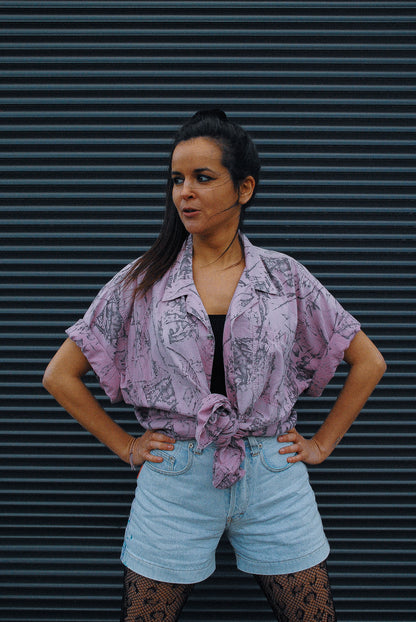 Model-in-front-of-garage-door-wearing-vintage-shirt-and-fresh-vintage-art-wear-jeans-short-in-light-jeans-color